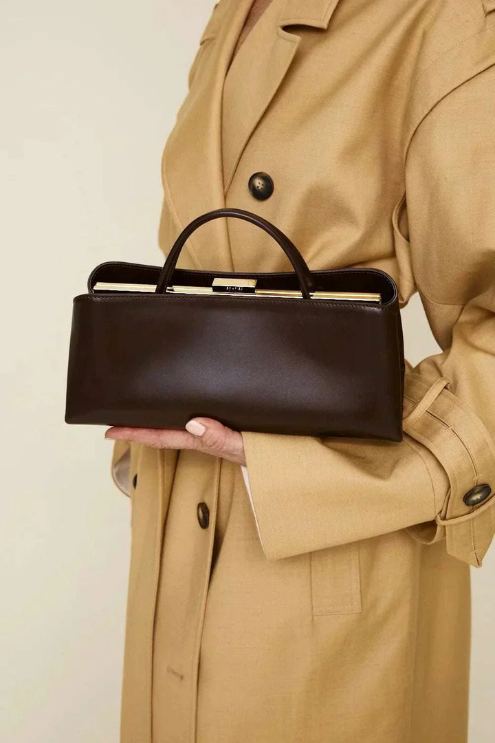 Elegant black Leclair handbag with structured frame held by person in beige coat