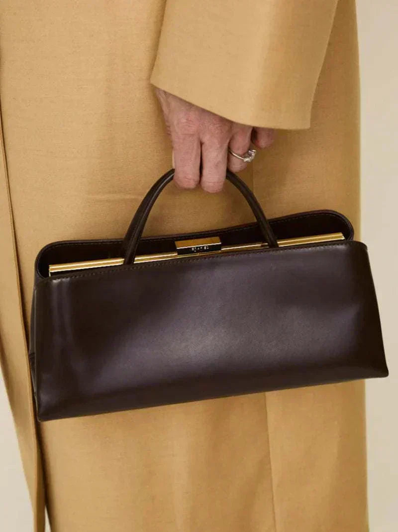 sleek black Leclair handbag with structured frame and gold closure in hand