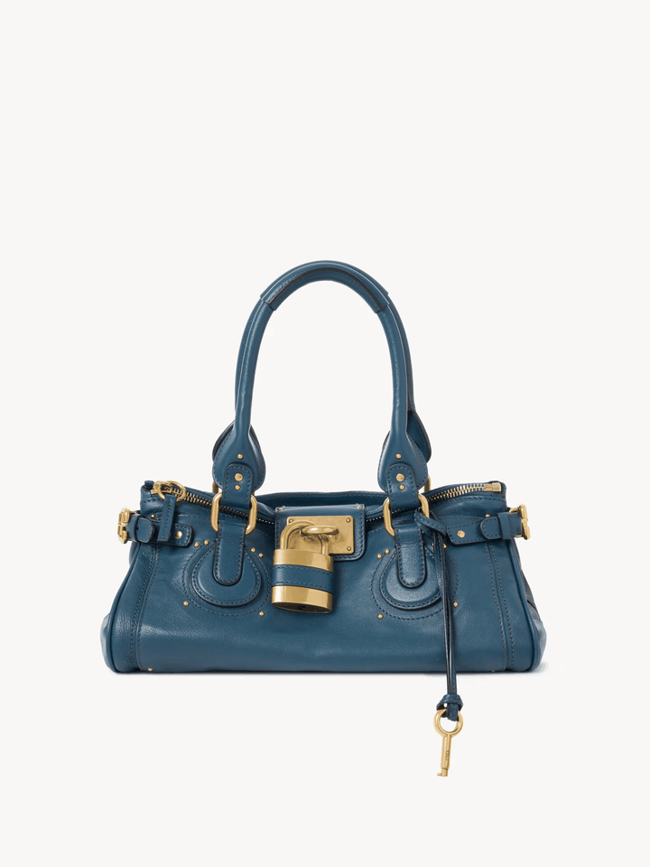 Blue Marcelle Lock Handbag with oversized gold lock, double handles, and smooth vegan leather