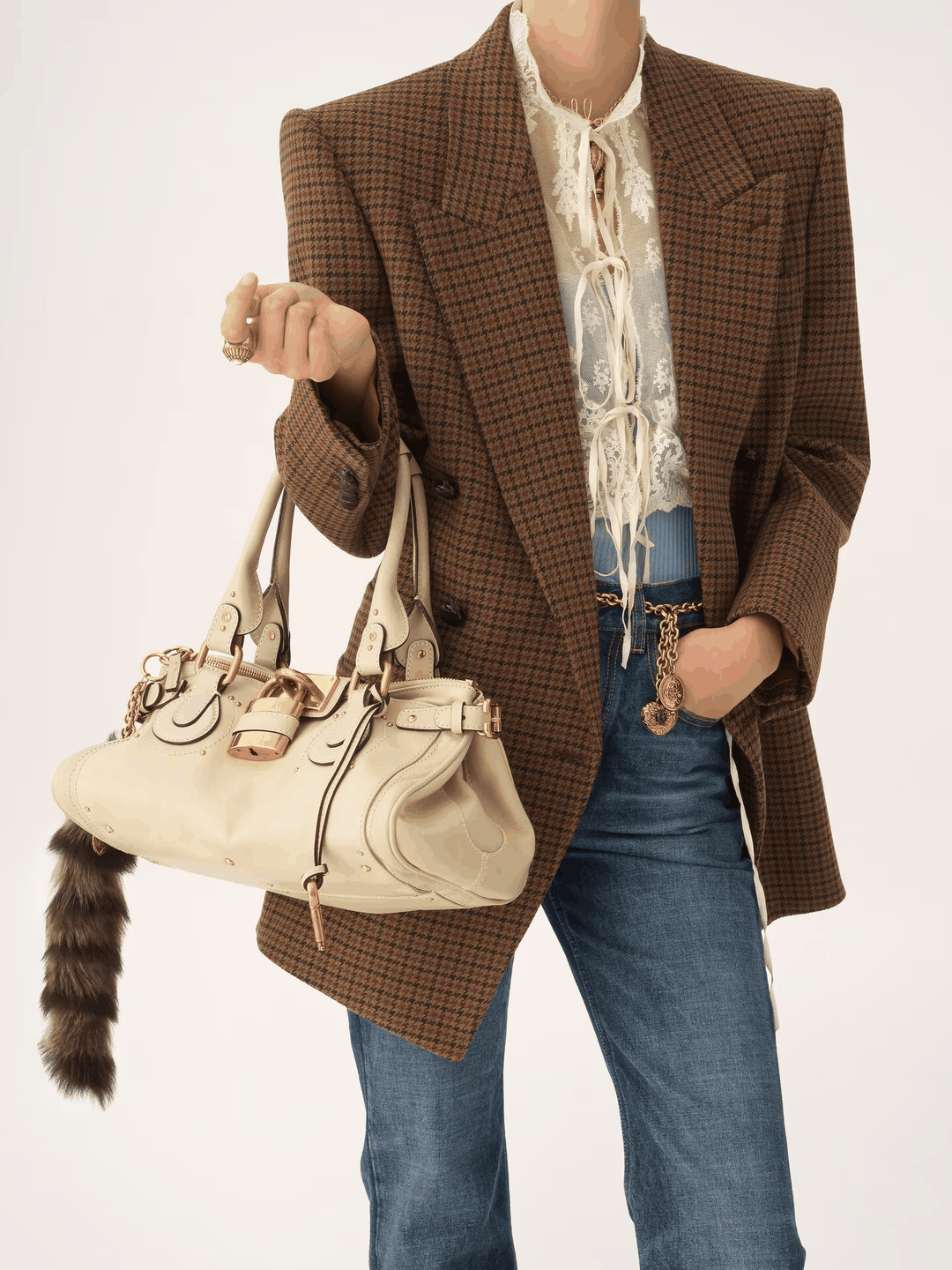 Marcelle Lock Handbag with oversized gold lock and double handles in smooth vegan leather, worn with brown check blazer and jeans