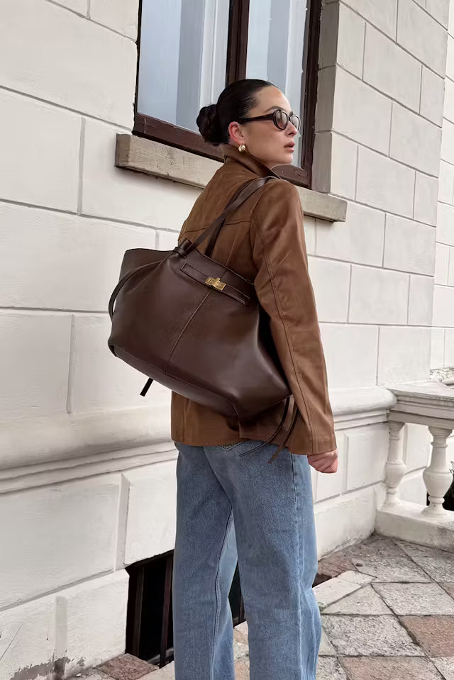 Woman carrying brown vegan leather Delair tote bag with relaxed silhouette outdoors