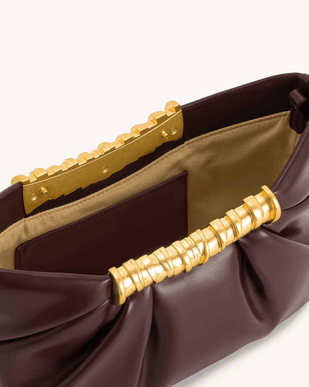 Lia clutch bag in smooth vegan leather with sculptural gold bar and gentle pleats, detachable strap included