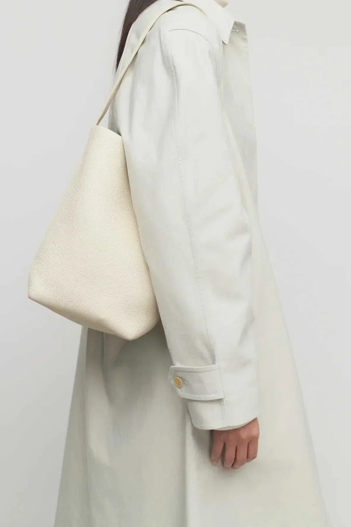 Cream-colored vegan leather shoulder bag with soft, unstructured design worn over shoulder