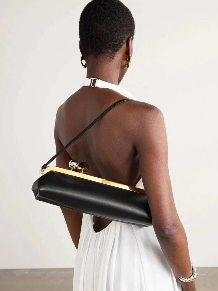 Black Venti clutch bag with gold frame and dual-metal clasp in smooth vegan leather worn over shoulder