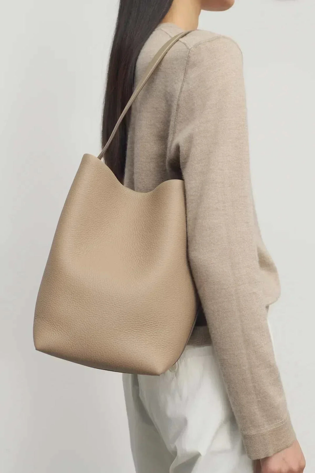 Beige grained vegan leather hobo shoulder bag with soft, unstructured silhouette worn over shoulder