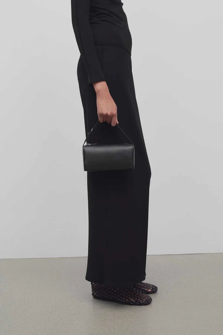 woman holding black mini structured handbag with elegant outfit