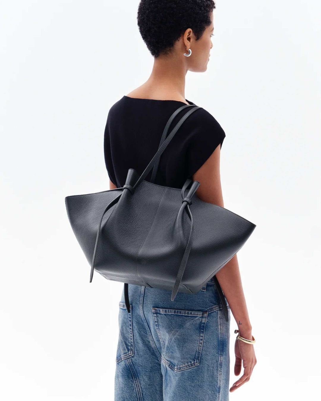 Woman carrying black Savina Tote Bag with knotted handles made from vegan leather