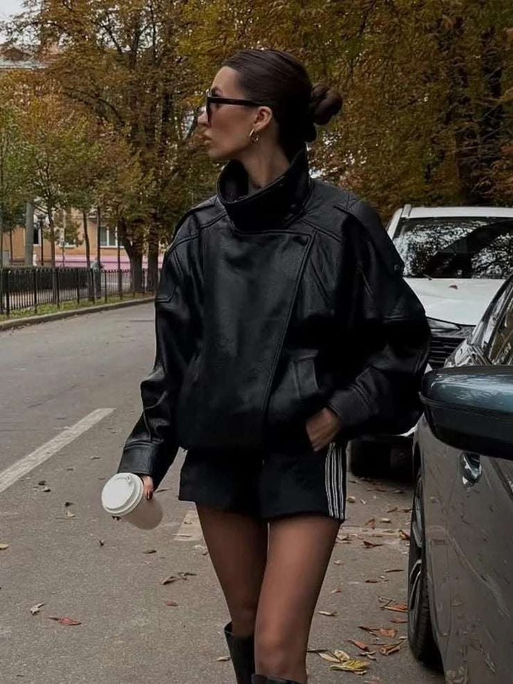 Oversized faux leather jacket with high funnel neck and asymmetrical front panel in outdoor autumn setting