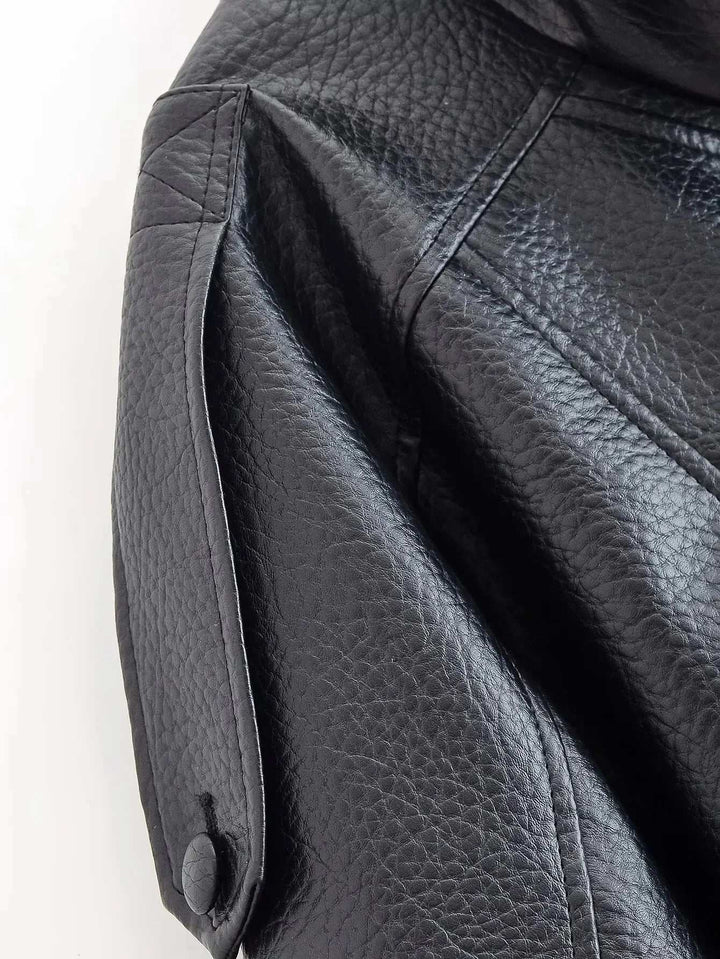 Close-up of black faux leather jacket sleeve with snap-button detail and textured leather funnel neck design