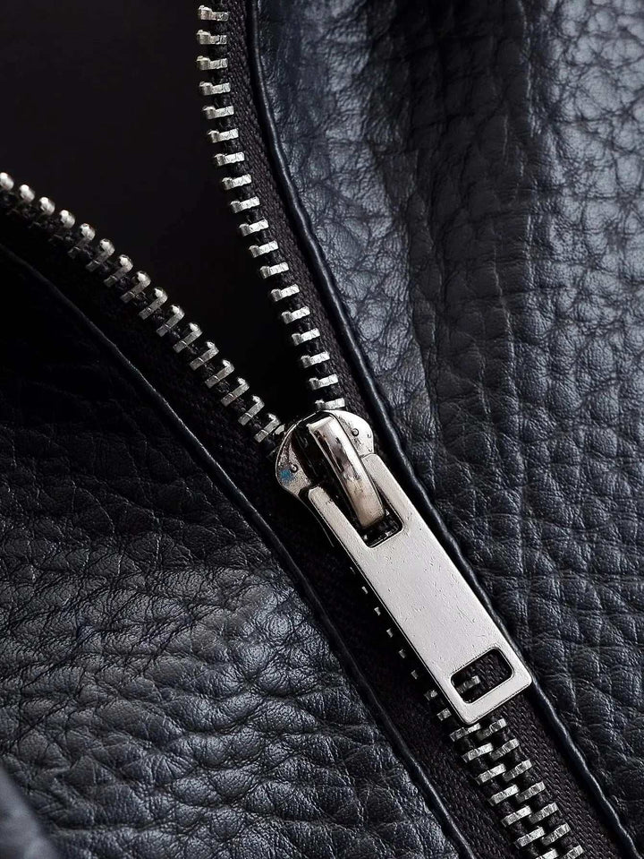 Close-up of textured black faux leather jacket with silver zipper on leather funnel neck design